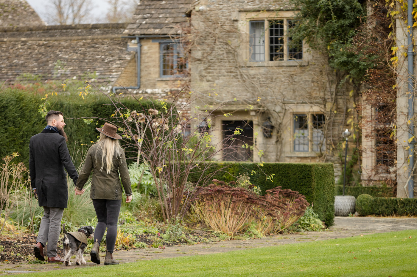 Happy guest dog enjoying the manicured garden grounds of Whatley Manor hotel