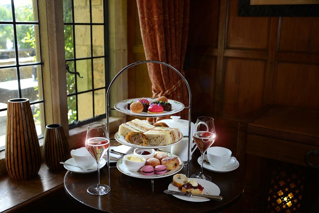 Tiered English Afternoon Tea stand with fresh fruit scones, clotted cream, delicate finger sandwiches, and patisserie
